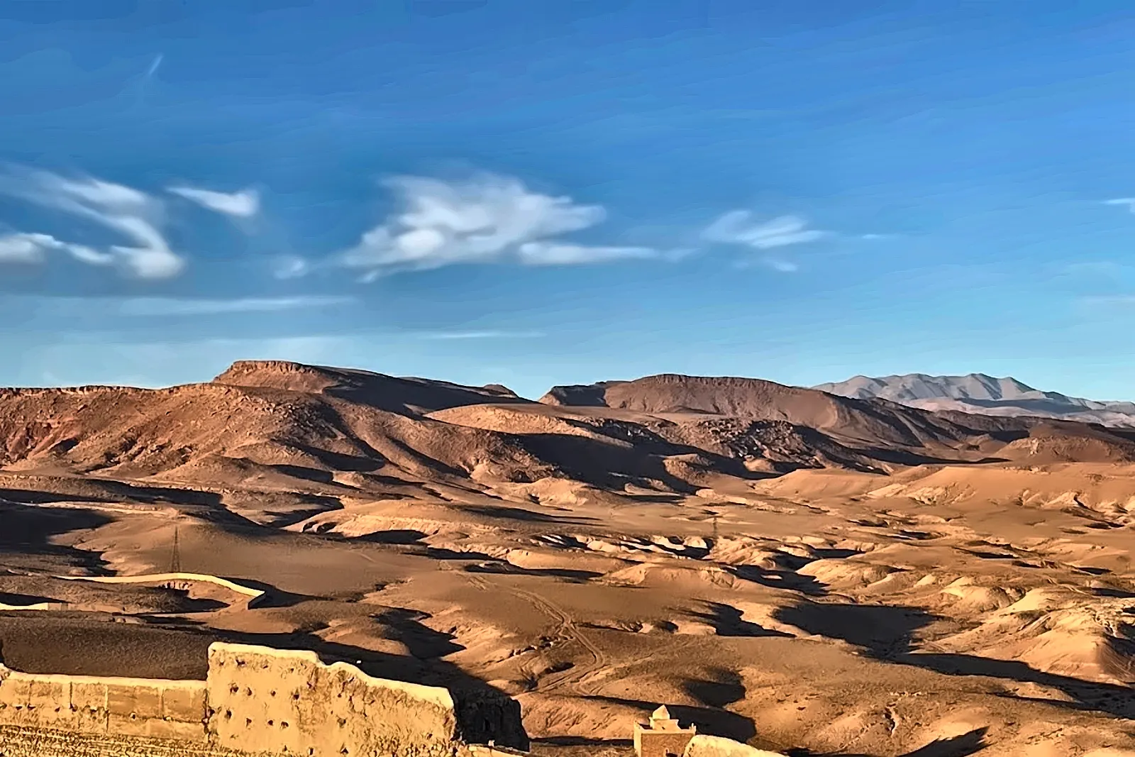 Kasbah di terra su un altopiano arido, con le montagne sullo sfondo
