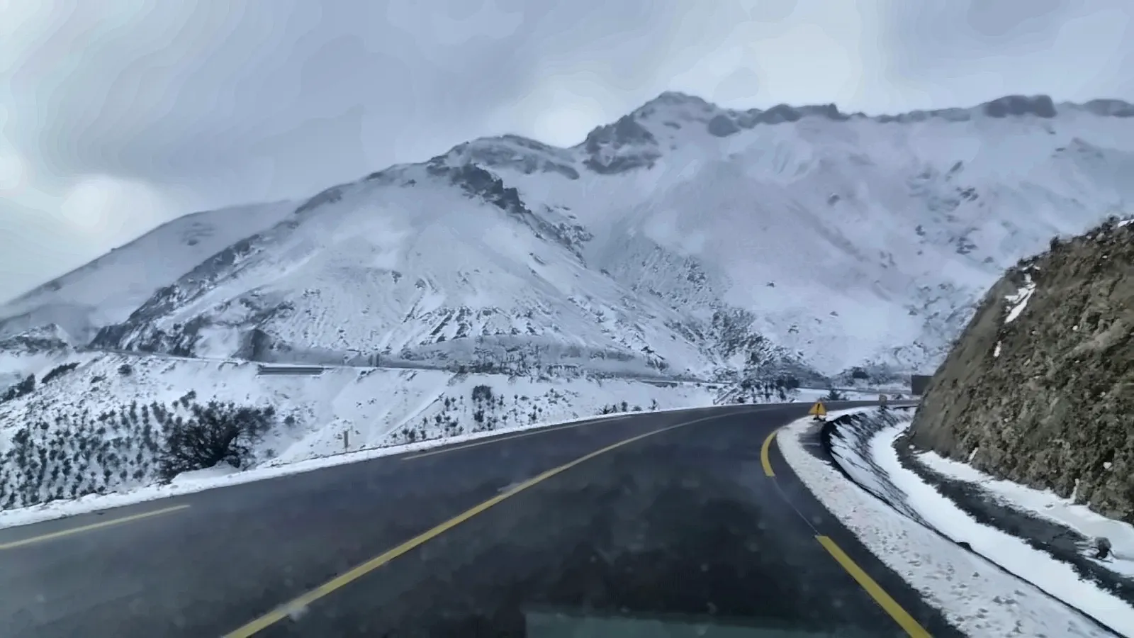 La strada asfaltata con le cime innevate davanti
