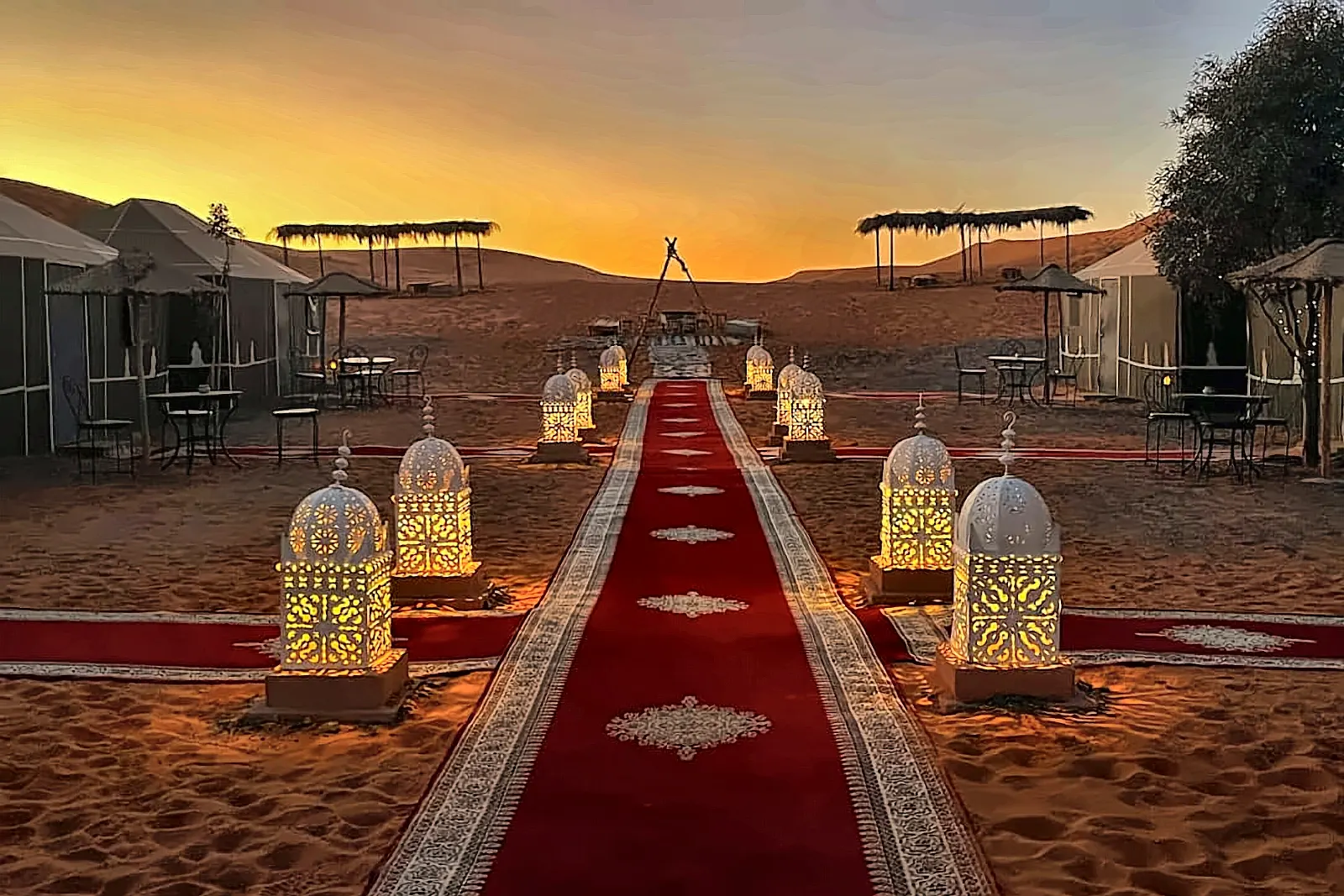 Il viale del campo di lusso con le lanterne accese e il tappeto rosso, al tramonto sulle dune