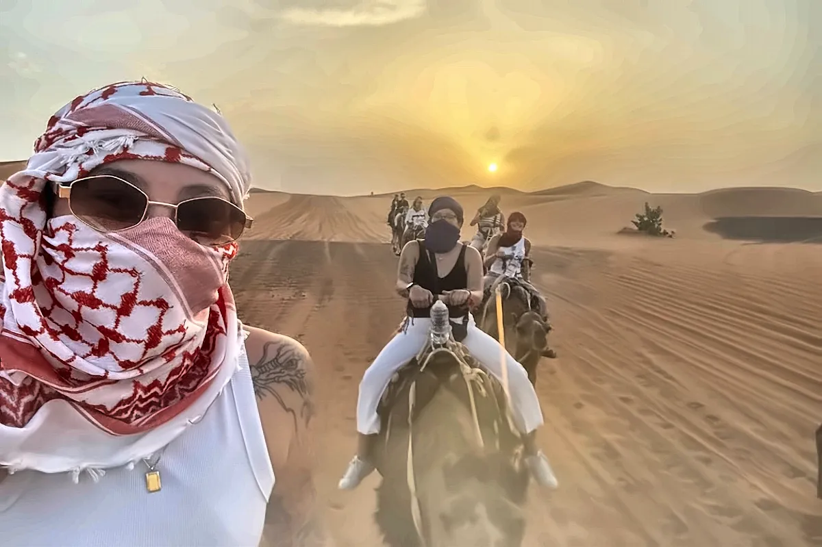 Viaggiatori con il turbante in sella ai dromedari al tramonto